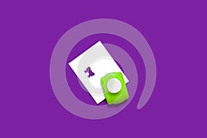 Green hole puncher with a paper on a purple background