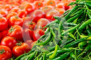 Green hot peppers and tomatoes on the market counter