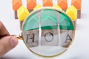 Person`s Hand Examining Homeowner Association Wooden Blocks photo