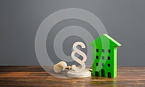 Green house and paragraph figurine with a judge hammer. Litigation in housing and real estate disputes. Norms and rules