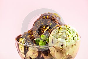 green ice cream decorated chocolate topping, pistachio nuts and mint on pink background