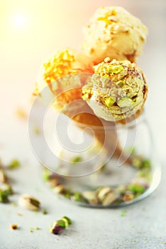 Green ice cream in waffle cone with chocolate and pistachio nuts on grey stone background. Summer food concept, copy