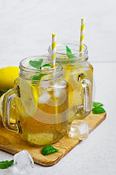 Green ice tea with lemon and mint in a glass jar.