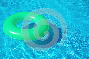 Green inflatable ring floating in swimming pool on sunny day