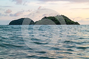 Green islands and reflected sea wave with blue, yellow sky color in background in the evening in Koh Mak Island at Trat, Thailand