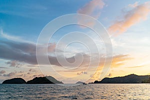 Green islands and reflected sea wave with blue, yellow sky color in background in the evening in Koh Mak Island at Trat, Thailand