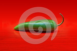 Green Jalapeno pepper on red background.