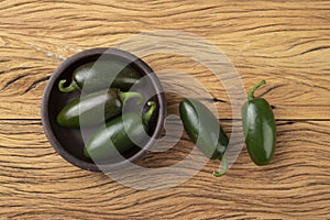 Green jalapeno peppers on a bowl over wooden table