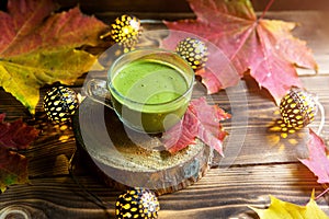 Green Japanese matcha tea with foam in transparent Cup on wooden table in autumn still life. Warm atmosphere and comfort, lights