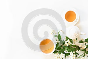 Green jasmin tea and jasmine flowers, cup of green tea on white background. Top view. Copy space.