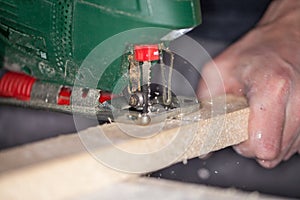 Green jigsaw saws a bright plank