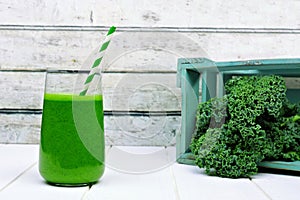 Green kale smoothie in a glass with crate of kale
