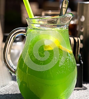 Green kiwi lemonade in glass pitcher, closeup