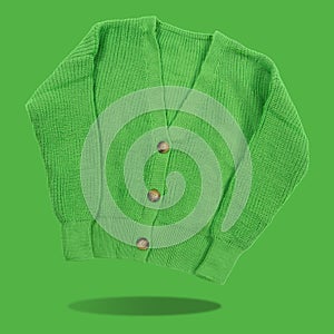 Green knitted women`s jacket, buttons fastened, levitates, concept, on a green background