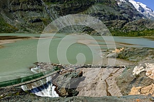 green lake with sandy islands and a bridge over a drain with a high curent photo