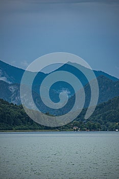 Green landscape of forested mountain range with lake view under cloudy sky