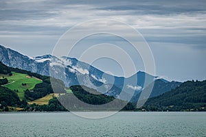 Green landscape of forested mountain range with lake view under cloudy sky