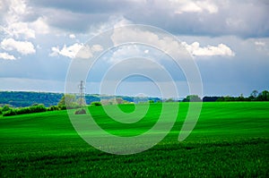 Green landscape and high voltage electrical power line. High voltage lines and power pylons in a green agricultural landscape with