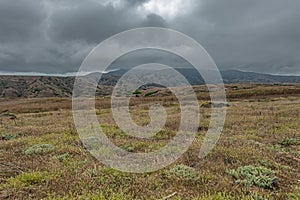 Green landscape under dark gray cloudscape, Santa Cruz Island, CA, USA