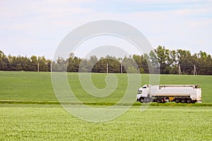 Green landscape with white tank trailer truck