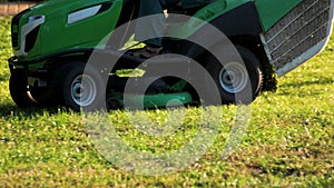 Green lawn mower cutting grass close up.