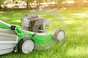 Green lawn-mower on fresh lawn at yard. Tools for cutting grass. Gardening and equipment service concept