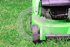 A green lawnmower in the garden. A lawn mower on the green grass. Gardening