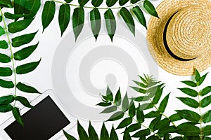 Green leaf branches, tablet and straw haton white background. flat lay, top view.