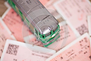 A green leather train model on a background of a pile of train tickets