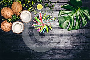 Green leaves of Monstera plant growing in wild, the tropical forest plant on black background. Lime coctail with cocktail tubes. T