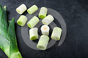 Green leeks sultan  oninon uncooked with herbs ingredients , on textured black background top view with space for text