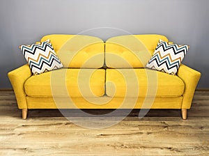 Green lemon yellow sofa with pillow. Soft lemon couch. Modern divan in interior gray wall wooden floor