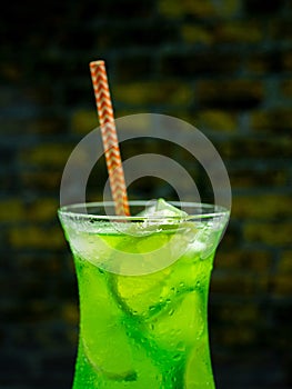 Green lemonade on the bar, green alcoholic cocktail, close-up drink with ice