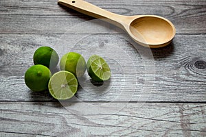 green lemons and wooden spoon on a rustic table photo