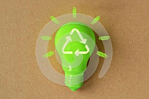 Green light bulb with recycling sign on recycled paper - Concept of ecology and recycling