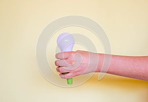 Green Light bulb on yellow background. Hand holds lamp. Free copy space. Concept of new idea, green energy