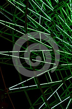 Green light fluorescent on structure of ferris wheel with dark night background