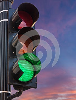 Green light on traffic signal against sunrise as concept for hope