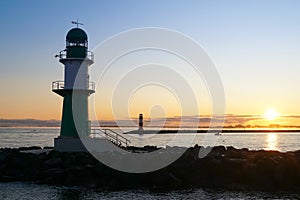 The green lighthouse in WarnemÃ¼nde and the Baltic sea during sunrise