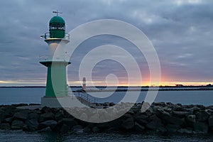 The green lighthouse in WarnemÃ¼nde and the Baltic sea during sunrise