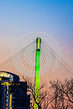 Green lighting of tower and cables of Bob Kerrey foot bridge with backdrop of River Front Condominiums Omaha Nebraska