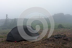 Green lightweight freestanding three-season 2-person tent on  hill in grass in the evening after rainstorm.  Jesenik mountains,