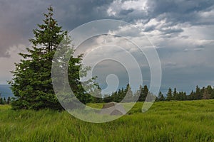 Green lightweight freestanding three-season 2-person tent on mravenecnik hill in grass in the morning after rainstorm