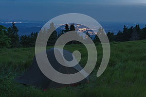 Green lightweight freestanding three-season 2-person tent on mravenecnik hill in grass in the evening