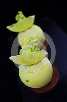 Green lime desserts on chocolate cookie with fresh lime slices and pistachio sponge