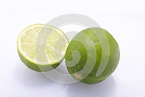 Green limes, cut in half and whole, isolated against a white background