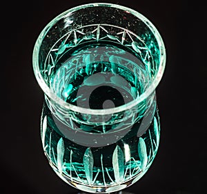 Green liquid in a crystal glass with dark background
