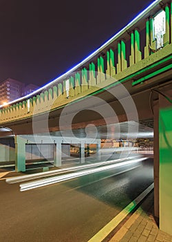 Green lit underpass with traffic in motion blur, Beijing night-time, China