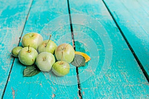 Green little homemade apples in water drops on the green wooden floor, Apple harvest