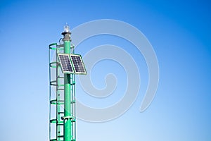 Green little lighthouse with staircase and solar cells against a blue sky - image with copy space